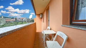 A balcony with a white table and chairs, a satellite dish, and a window overlooking a residential area. - Apartment 1858/143214 (Istria - Valbandon), 1000m from the beach (Valbandon)