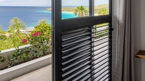 A balcony with a view of the ocean and a tropical landscape. - Villa Neshi, Spacious 5-bedroom villa in charming Cas Abou Resort with AC, WiFi (Willemstad)