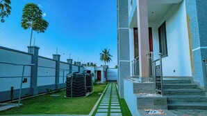 A modern building with a paved pathway leading to a set of stairs. - Villa - Sleeps 8 - Parking - Balcony (Dar es Salaam)
