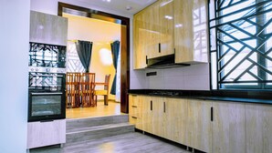 A modern kitchen with wooden cabinets, a built-in oven, and a dining area with a table and chairs. - Villa - Sleeps 8 - Parking - Balcony (Dar es Salaam)