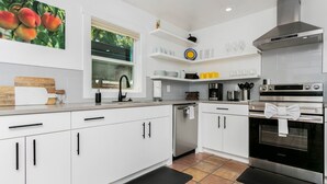 Una cocina moderna con armarios blancos, una campana extractora de acero inoxidable y un horno empotrado.