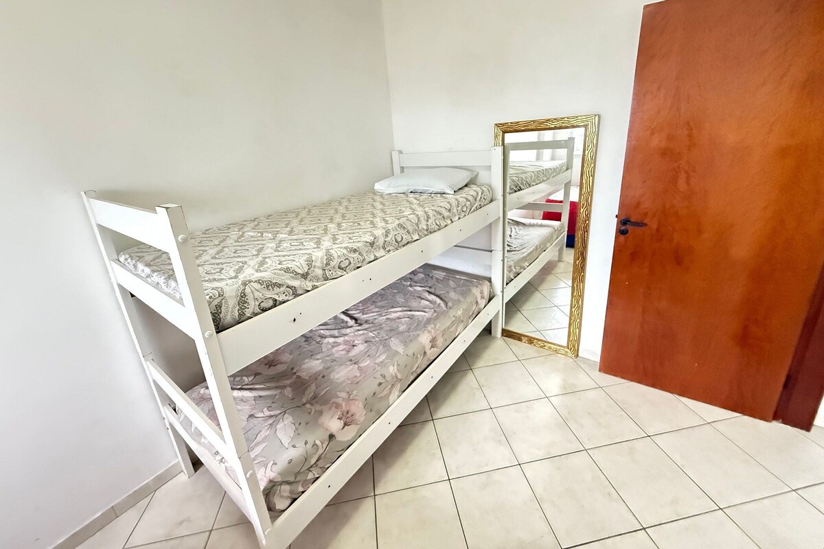 A bunk bed room with a wooden door and tiled floor.
