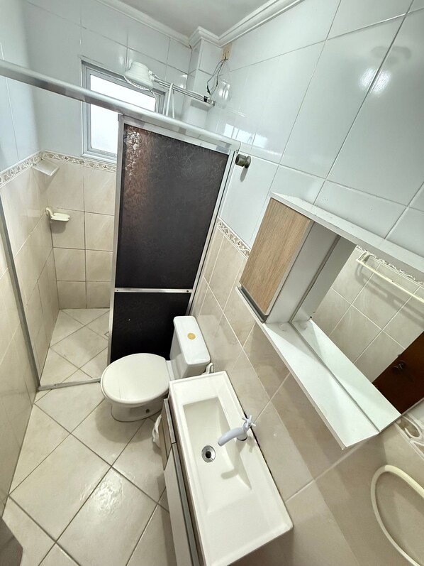 Een kleine badkamer met toilet, wastafel en douche.