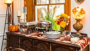 Una mesa de bufé con alimentos, una lámpara decorativa y un jarrón con flores.