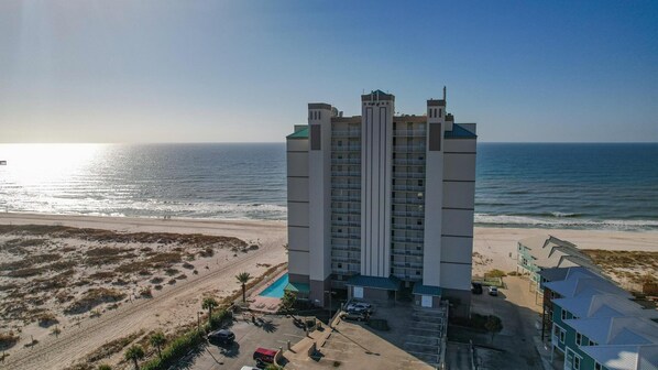 A high-rise hotel with a pool, located near a beach with ocean views.