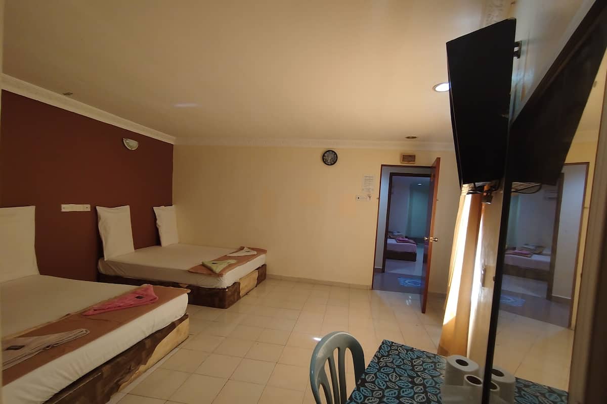 A hotel room with two beds, a small table with a chair, a clock, and a door leading to another room.