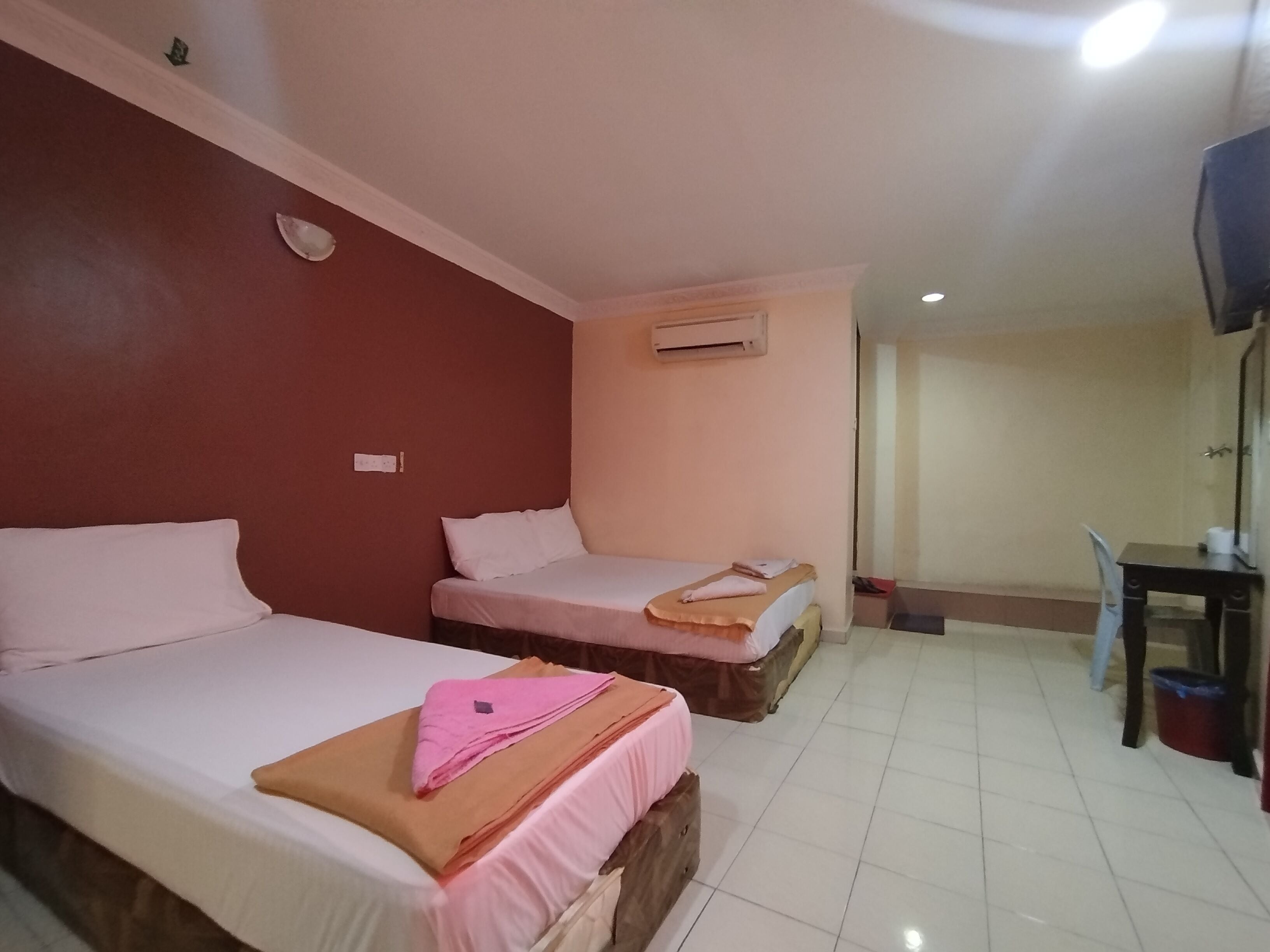 Habitación de hotel con dos camas, un escritorio y un equipo de aire acondicionado.