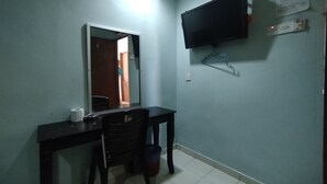 Ein kleines Zimmer mit Schreibtisch, Stuhl und einem an der Wand befestigten Fernseher.