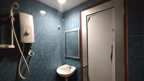 Ein Badezimmer mit einem weißen Waschbecken, einer Handbrause, einem wandmontierten Spiegel und einer Tür mit Holzrahmen.