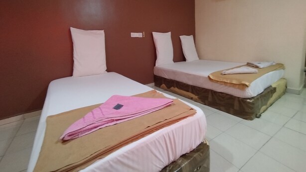 Ein Hotelzimmer mit zwei Betten, jeweils mit weißer Bettwäsche und Kissen, und einer braunen Decke auf einem Bett.