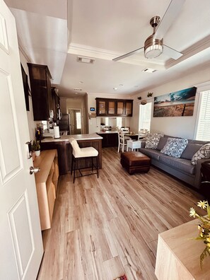 A modern kitchen with dark cabinets, a central island, and a dining area with a sofa and chairs.
