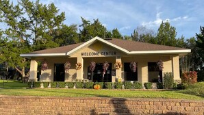 A building labeled "WELCOME CENTER" with a brick facade, a flat roof, and a front porch with flower arrangements. - Get 10% off on weekly stay or 15% on monthly stay. Fully equipped cabin. CR. Fl (Crystal River)
