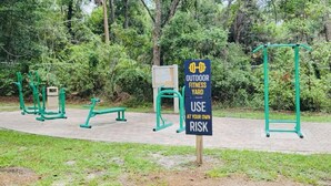 An outdoor fitness yard with exercise equipment and a sign warning to use at your own risk. - Get 10% off on weekly stay or 15% on monthly stay. Fully equipped cabin. CR. Fl (Crystal River)