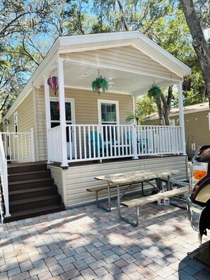 A single-story house with a covered porch, a picnic table, and a barbecue grill.