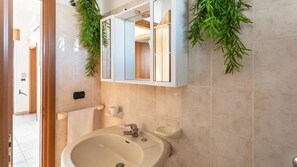 Een badkamer met een wastafel, spiegel en handdoekhouder.