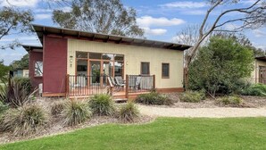 A two-story building with a balcony, large windows, and a grassy yard. - The Purple Hen Hideaway Ramada (Cowes)