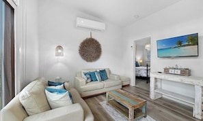 A living room with a sofa, coffee table, wall-mounted TV, and decorative wall art.