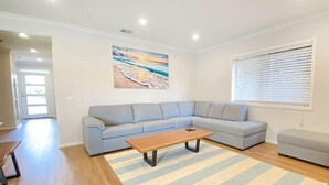 Een woonkamer met een grijze modulaire bank, een houten salontafel en een gestreept vloerkleed.