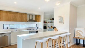 Een moderne keuken met witte kasten, een centraal eiland met barkrukken en een ingebouwde oven.