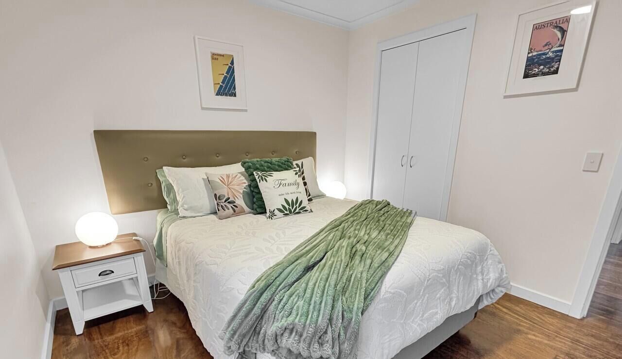 A bedroom with a bed, nightstand, wall art, and a door.