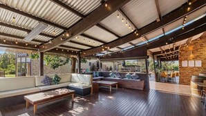 An outdoor patio area with wooden flooring, seating arrangements, and a stone wall. - Island Haven Villa Ramada Resort (Cowes)