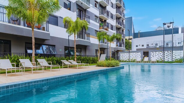 A modern hotel with a swimming pool, lounge chairs, and palm trees. - Piscina-AC-Academia-Brazilian Corner (São Paulo)