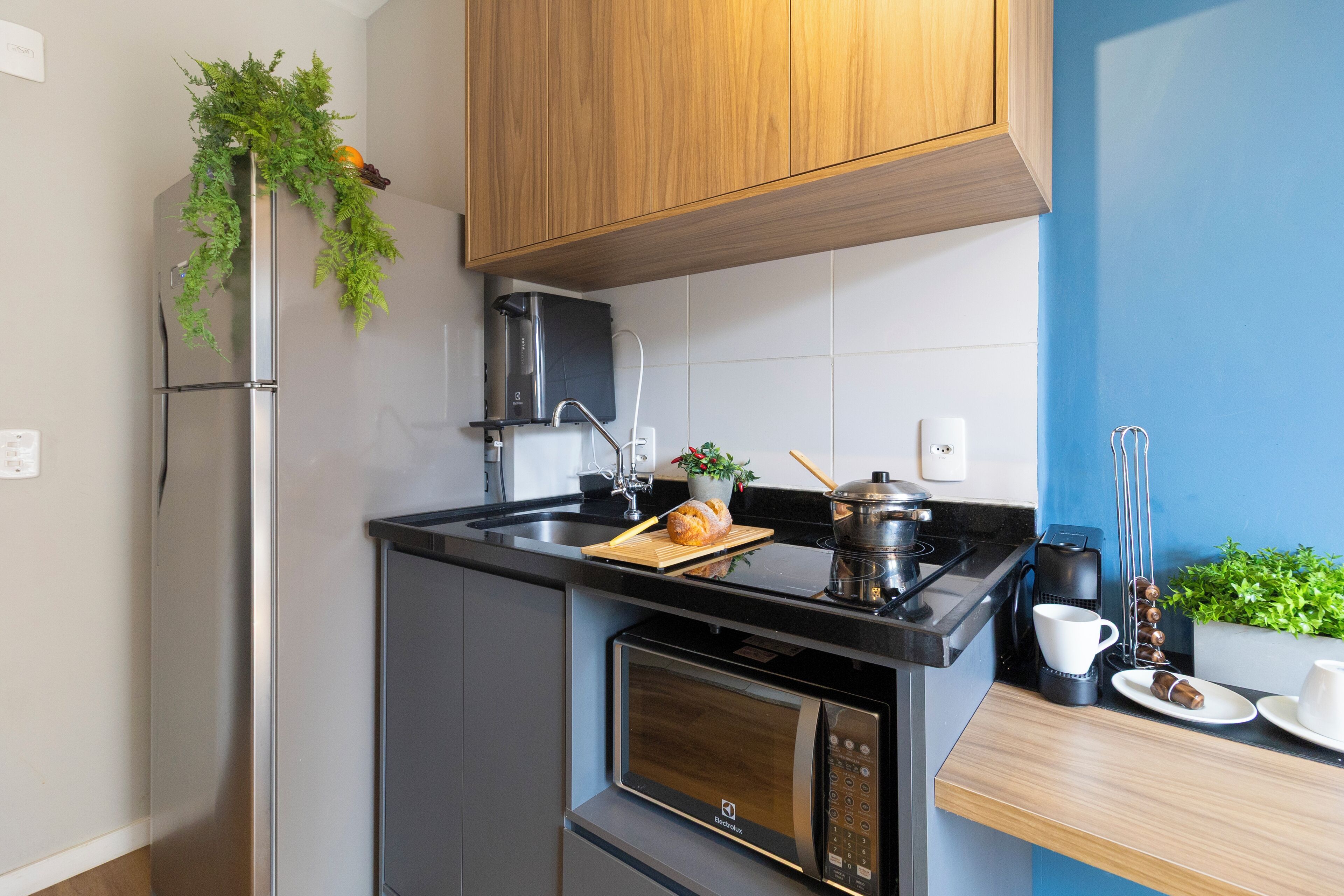 A compact kitchen with a built-in microwave, a coffee maker, and a small stove.