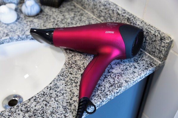 Un secador de pelo rosa con 2200W sobre una encimera de granito.