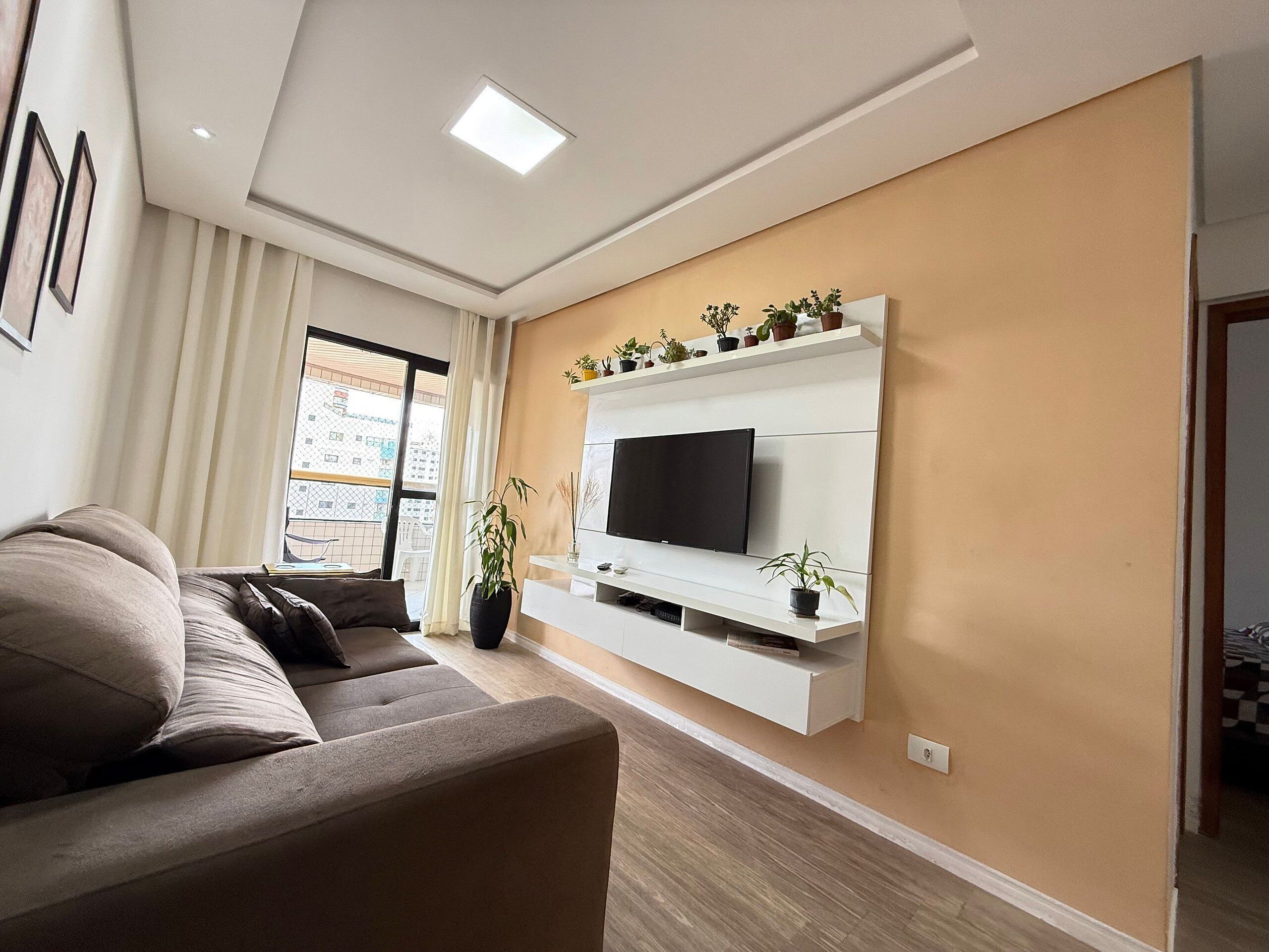 A modern living room with a sofa, TV, and potted plants.