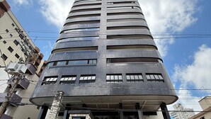 Een hoog, modern gebouw met een gebogen gevel, meerdere ramen en een stenen basis.