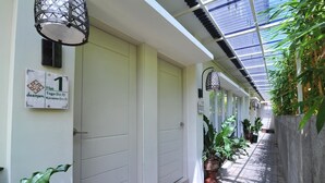 A corridor with doors, a doormat, and potted plants. - Dasinem Family Homestay (Pogung Lor)