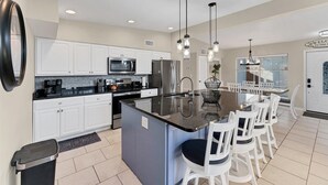 A modern kitchen with white cabinets, stainless steel appliances, and a central island with bar stools.