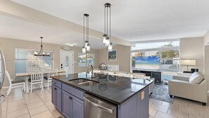 A modern kitchen with a central island, stainless steel appliances, and pendant lighting.