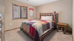 A bedroom with a wooden bed frame, a quilt, a small wooden nightstand, and a window with blinds. - 1 Bedroom, sleeps  up to 6, Steps to Table Rock Lake! Ticket Deals! (Branson)