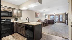 A kitchen with dark wood cabinets, a black stove, and a granite countertop. - 1 BDRM, Lake Community Condo near Silver Dollar City!  Ticket Deals and Resort Perks (Branson)