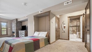 A bedroom with a large bed, a stone fireplace, a television, and a bathroom with a shower and bathtub. - 1 BDRM, Lake Community Condo near Silver Dollar City!  Ticket Deals and Resort Perks (Branson)