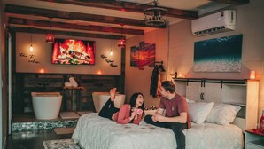 Un dormitorio acogedor con chimenea, un televisor grande y una cama con vista al mar.