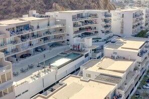 A modern multi-story hotel with balconies, a rooftop pool, and a view of the surrounding landscape. - Ocean View, 2 Infinity Pools, Pedregal, 3 King bed (Cabo San Lucas)