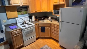 Una cocina con armarios de madera, estufa, refrigerador y lavaplatos.