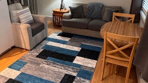 Una sala de estar con un sofá, una mesita de madera, una lámpara y un tapete azul y negro estampado.
