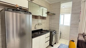 Eine moderne Küche mit einem Edelstahl-Kühlschrank, einem eingebauten Backofen und einer schwarzen Arbeitsplatte.