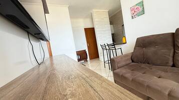 Una sala moderna con una mesa de comedor de madera, un sofá marrón y una cocina al fondo.