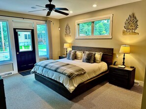 A bedroom with a bed, two bedside tables, a ceiling fan, and a window.