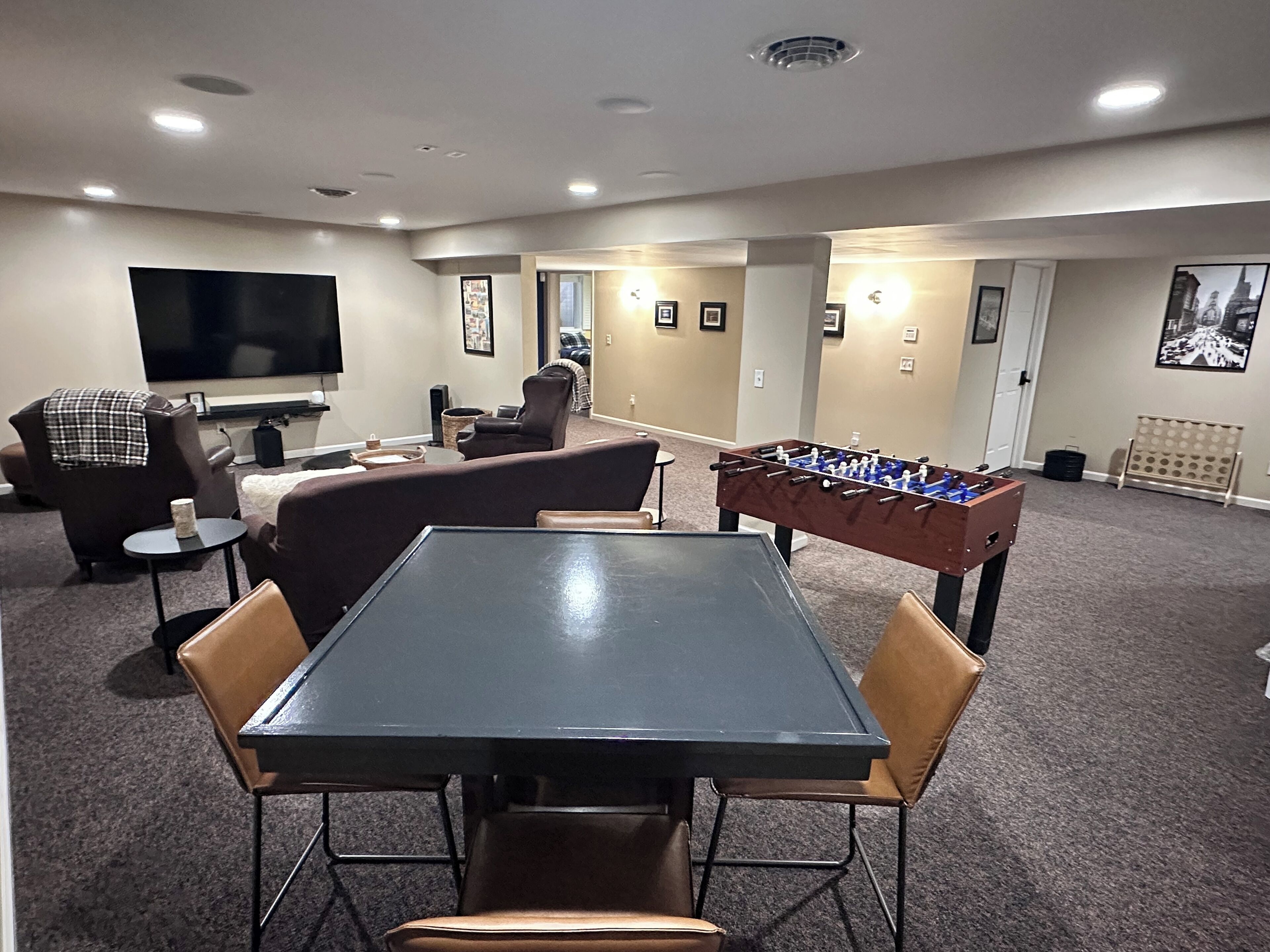 Uma sala de estar com mesa de futebol, televisão de tela plana, sofá e mesa de centro.