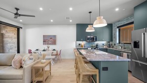 A modern kitchen with a central island, stainless steel appliances, and a dining area with a table and chairs. - Montclair Zion - a luxurious Villa that embodies comfort and style with balcony (Springdale)