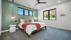 A bedroom with a bed, a nightstand, a ceiling fan, and two windows with a view of the outdoors. - Montclair Zion - a luxurious Villa that embodies comfort and style with balcony (Springdale)