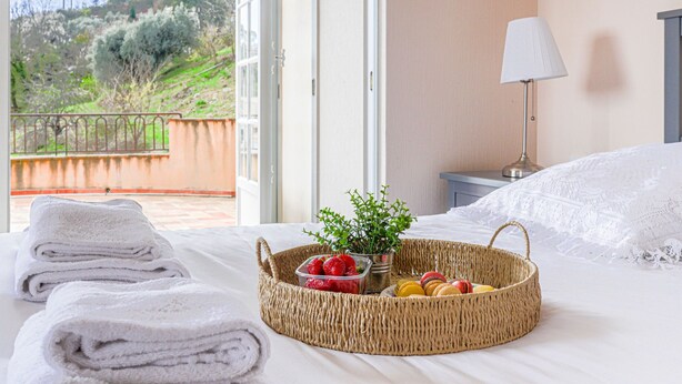 A hotel room with a bed, a wicker basket with strawberries and macarons, a lamp, and a view of the outdoors. - Le Mas de Gattières by Interhome (Vence)