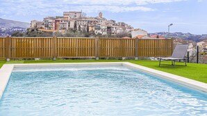 A swimming pool with a wooden fence, a chair, and a view of a town with buildings on a hill. - Le Mas de Gattières by Interhome (Vence)