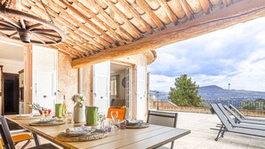 A dining area with a table set for four, a rustic ceiling, and a view of the landscape. - Le Mas de Gattières by Interhome (Vence)