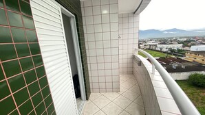 A narrow balcony with a view of a cityscape and mountains in the distance. - Pé Na Areia Praia da Ocean II (Praia Grande)